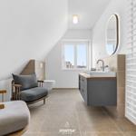 Badezimmer mit Waschtisch, Toilette und Sitzgelegenheit unter Dachschrägen.
