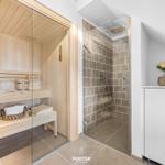 Sauna mit Holzbank und Dusche mit Steinwand