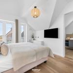 Schlafzimmer mit Dachschrägen, TV und Anschluss an Badezimmer.