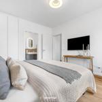 Schlafzimmer mit Bett, TV und Badezimmer im Hintergrund.