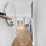 Haus mit Holzboden und runden Spiegel. Durchgang zur Essnische mit Tischen und Stühlen.