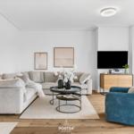 Wohnzimmer mit Sofa, Sessel, Couchtisch und Fernseher.