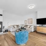 Wohnzimmer mit Sofa, Kamin und Fernseher auf Holzkonsole.