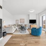 Wohnzimmer mit Kamin, Sofa, TV und blauem Sessel.