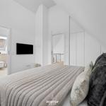 Bedroom with double bed, TV, and view into the modern bathroom.