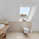 Bathroom with shower, toilet, and sink under sloped roof