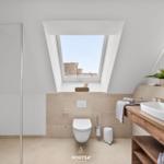 Badezimmer mit Dusche, Toilette und Waschbecken unter Dachschrägen