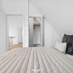 Schlafzimmer mit Dachschrägen, Bett und Kleiderschrank. Durchgänge zu weiteren Räumen.
