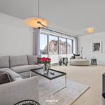 Wohnzimmer mit Sofa, Couchtisch und Blick auf Dächer.