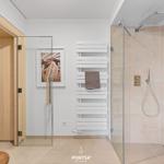 Dusche mit Regenduschkopf und Heizkörper. Sauna und Wandbild sind sichtbar.