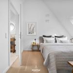 Schlafzimmer mit Dachschräge, Bett, Nachttisch und Blick auf Dachfenster.