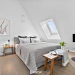 Schlafzimmer mit Dachschräge, Bett, Fenster und Fernseher.