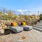 Outdoor area with gray sofa, yellow cushions, and stone stairs.