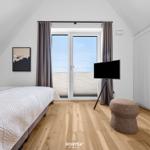 Bedroom with bed, TV, and balcony view.