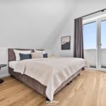 Bedroom with double bed, wooden floor, and large window with view.
