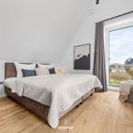 Bedroom with double bed, wooden floor, and large window with view.