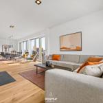 Living room with sofa, fireplace, and dining area with large windows.