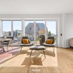 Living and dining area with wooden floor, seating, and view of the garden.