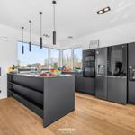 Modern kitchen with dark cabinets, kitchen island, and large windows.