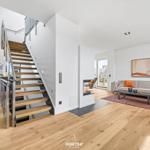 Apartment with wooden floors, staircase, and modern living area with sofa and fireplace.