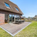 House with roof terrace, dining area, and garden. Wooden terrace and seating group.