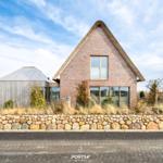 Modern villa with thatched roof and stone wall