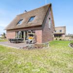 House with thatched roof and terrace with garden