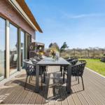 Deck with table and chairs, view of lawn and sky.