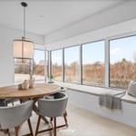 Dining room with round table, gray chairs, and large window view.