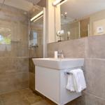 Bathroom with shower, sink, and mirror.