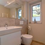 Bathroom with sink, toilet, and window with view outside.