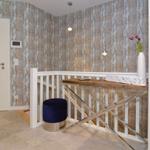 Entrance area with wooden bench, blue ottoman, and wood-patterned wallpaper.