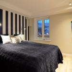 Bedroom with striped wall, bed, window, and wall-mounted TV.