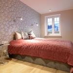 Bedroom with bed, window, and wall with round decorative elements.