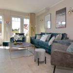 Living room with sofa, armchairs, and table. Doorways to outdoor area.