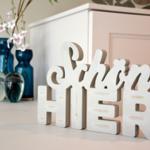 Beautiful here - wooden letters and flower vases on a white cabinet