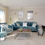 Living room with blue sofa, seating, and windows with view.