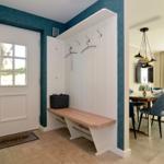 Entrance with coat rack and bench. View into dining room with table and chairs.