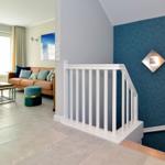 Living area with sofa, table, and staircase with blue wall.