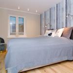 Bedroom with bed, window, and wall lighting.