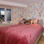 Bedroom with bed, window, and patterned wall covering.
