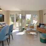 Living and dining area with sofa, dining table, and glass doors to terrace.