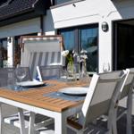 Terrace with table, chairs, and sunshade in front of white house