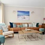 Living room with sofa, armchair, and coffee table. Wall art and mirror are visible.