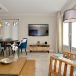 Living and dining area with TV, sofa, and dining table with blue chairs.