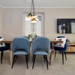 Dining area with blue chairs and TV wall.