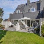 House with terrace, garden, and seating under sunshade.