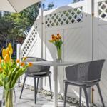Terrace with table, two chairs, and tulips in vases. White wooden fence and umbrella.