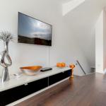 TV mounted on wall, living room with wooden floor and modern furniture