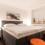 Bedroom with double bed, nightstand, and window with blinds.